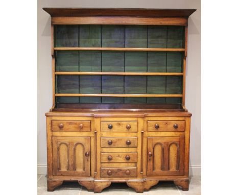 * A George III oak and fruitwood dresser, the high back with a flared cornice above a painted interior and three enclosed she