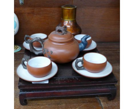 An oriental terracotta four setting tea service on a wooden stand and a metal oriental tea caddy