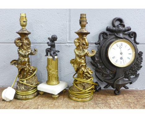 A pair of brass cherub table lamps, a cherub figure and a cast metal wall clock