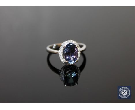 A 14ct white gold tanzanite and diamond halo ring, the central, oval-cut, medium-blueish/purple tanzanite weighing 2.05 carat