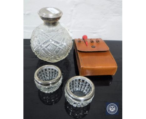 A cut glass silver lidded perfume bottle, a pair of silver rimmed salts and a hip flask in a leather pouch 