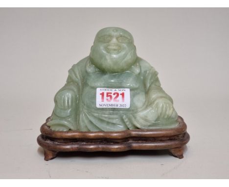 A Chinese carved green jade Buddha,&nbsp;on fitted wood stand, 11cm high. 