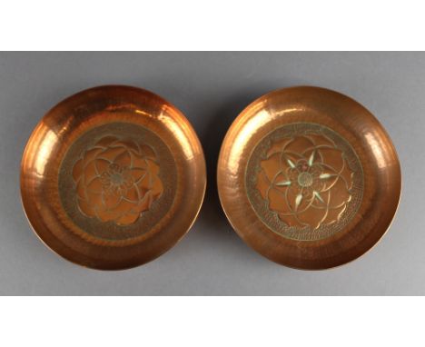 Two similar Keswick School of Industrial Arts circular planished copper dishes, each with raised flowerheads to centres, each