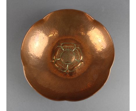 A Keswick School of Industrial Arts planished copper bowl with shaped rim, embossed to centre with a flowerhead, 21cm diamete