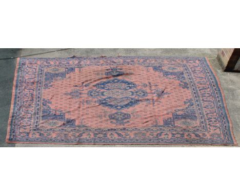 A Turkish carpet, woven in green and blue with central medallion, spandrels and geometric motifs on a salmon ground, 410cm x 