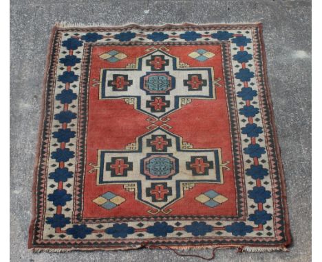 A rug of Caucasian design, woven with two medallions on a red ground, 197cm x 136cm Light staining and wear