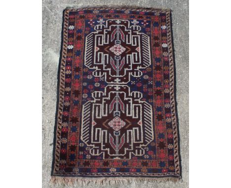 A Beluch rug, woven with two geometric medallions on a blue ground, 138cm x 82cm Light wear