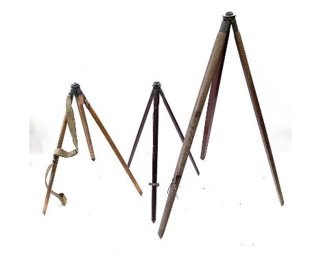 An early 20th century theodolite tripod stand with brass lacquered mounts, height 98cm, together with two other theodolite tr