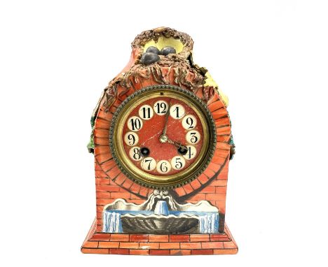 A French porcelain mantel clock, late 19th century, the case surmounted by a bird's nest, with faux brick painted front and p