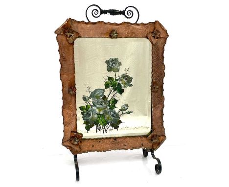 A late Victorian mirrored firescreen, painted with roses and within an engraved copper frame with wrought iron stand, height 