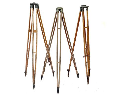 A 20th century theodolite tripod stand with metal mounts and impressed broad arrow mark, height 164cm together with two other