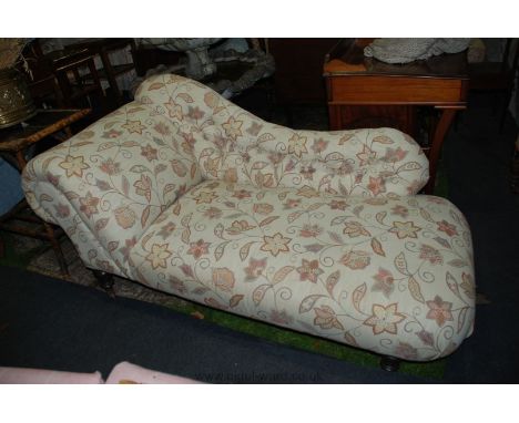 An Edwardian Chaise Longue with button back and standing on turned legs, recently re-upholstered with stylised beige fabric