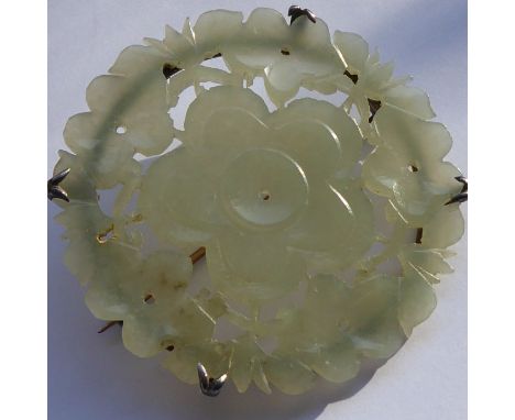 A large early 20th century circular carved celadon jade brooch (probably Chinese) of pale colour; the five-petal flower centr