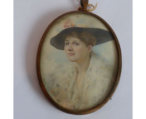 An early 20th century oval shoulder-length portrait of a young lady with wide brimmed hat, pearl necklace and feathered jacke