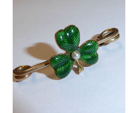 A small yellow metal bar brooch centrally decorated with a green enamel shamrock centred with a small pearl, 3cm wide, total 