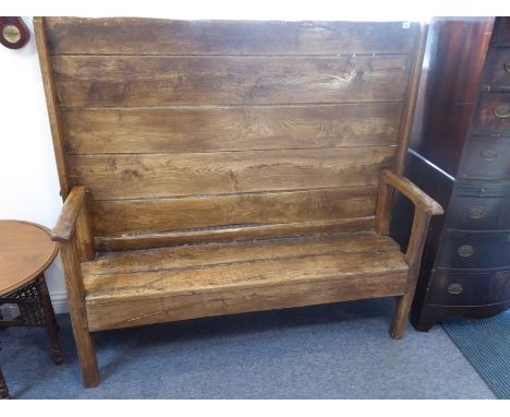 An early 18th century elm monk's bench, the patinated planked table top rotating on iron pegs to form the back of the settle,