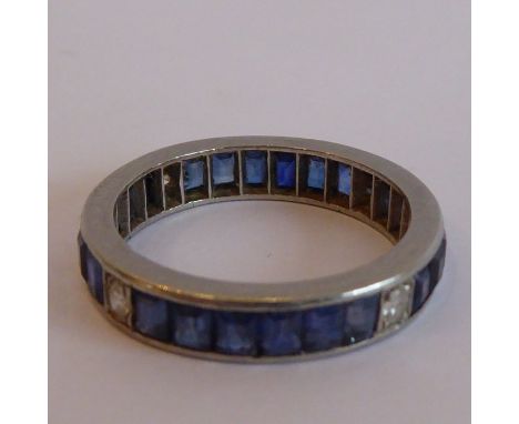 A heavy white-metal eternity ring set with sapphires interspersed with four diamonds at the N,E, S and W positions, ring size