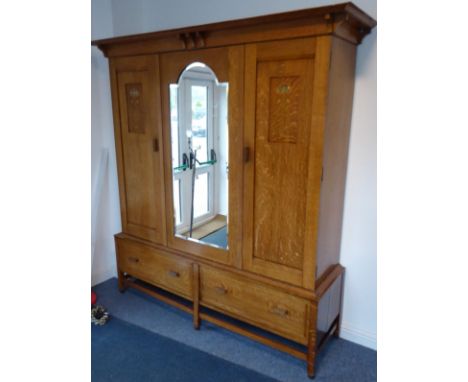A good and large early 20th century Arts and Crafts-style oak double wardrobe, the single broken-arch hand-bevelled mirror pl