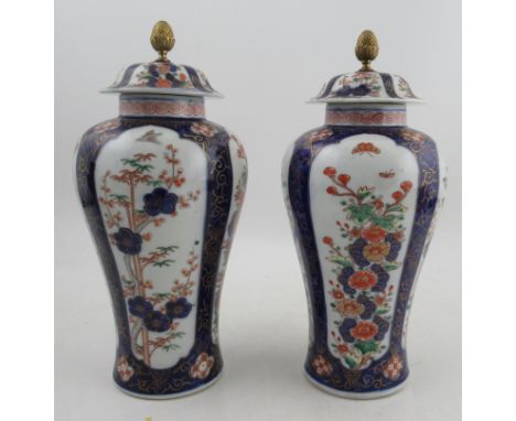 A pair of 20th century Chinese covered vases, decorated with panels of flowers, red seal mark to the base, height 12.5ins