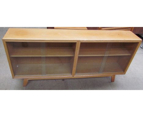 A mid 20th century light oak bookcase with glazed doors on splayed legs