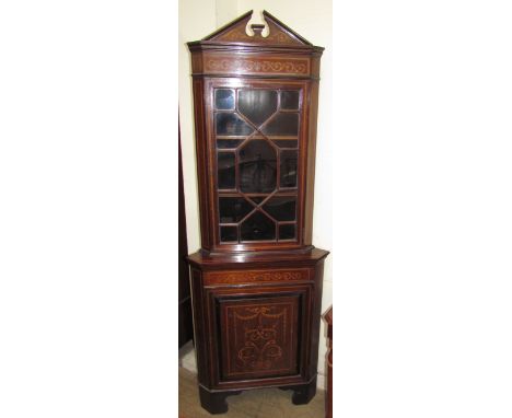 An Edwardian mahogany standing corner cupboard, the moulded architectural cornice above a single glazed door with glazing bar