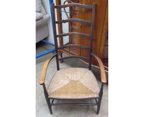 A late 19th century ladder back elbow chair with a rush seat on tapering legs