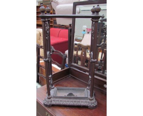 A cast iron stick stand with three openings and a drip tray