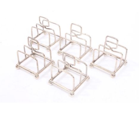 Five 1920s silver individual toast racks of tubular form, with loop handles, on four ball feet (Sheffield 1922), William Hutt