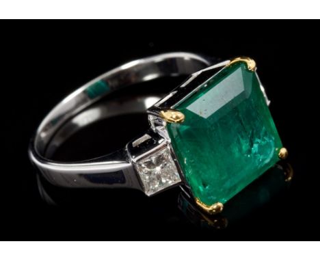 Emerald and diamond three-stone ring with a rectangular step cut emerald estimated to weigh approximately 4.77 carats, flanke