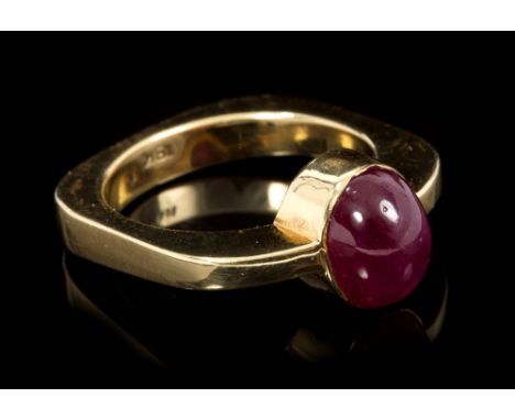 Ruby single stone ring with an oval cabochon ruby measuring approximately 9mm x 7mm x 4.5mm on modern squared gold band. Ring