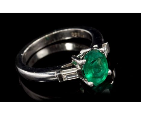 Emerald and diamond three-stone ring with an oval mixed cut emerald measuring approximately 8.00mm x 6.00mm x 4.03mm, flanked