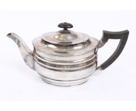 George V silver teapot of oval ribbed form, with angular ebony handle and hinged domed cover with ebony finial, on a reeded o