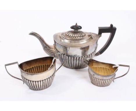 George V silver three piece tea set - comprising teapot of half-fluted form, with ebony angular handle and hinged domed cover