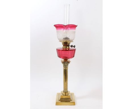 Early 20th century oil lamp with etched ruby glass shade and reservoir, raised on brass Corinthian column and square stepped 