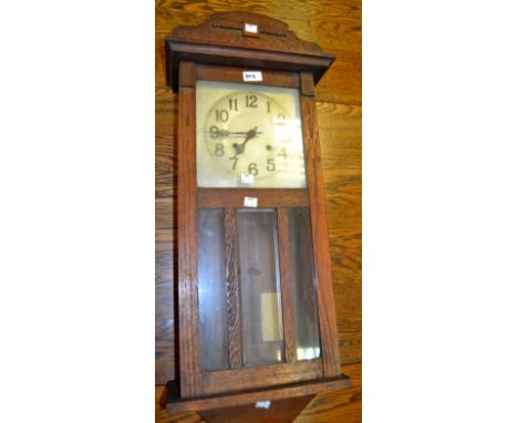 An oak pendulum wall clock, twin winding holes c.1930