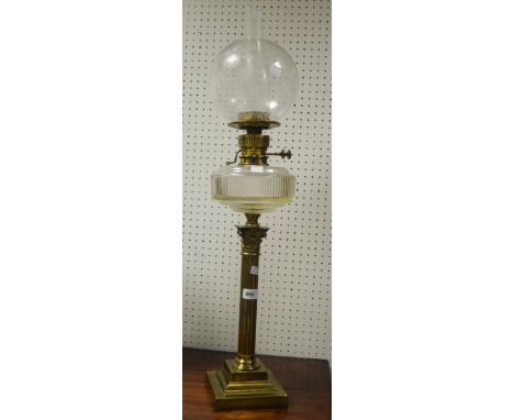 A brass oil lamp, clear glass reservoir, acid etched shade