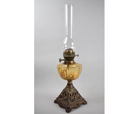 A Late Victorian Oil Lamp with Cast Pierced Metal Base, Amber Glass Reservoir and Plain Chimney, Overall 57cms 