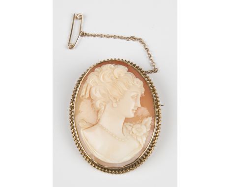 A 9ct gold mounted oval shell cameo brooch, carved as a portrait of a lady with a flower within a twisted wirework border, Bi