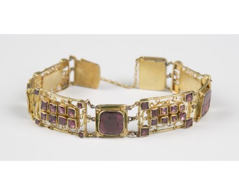 A mid-19th century gilt metal, foil backed flat cut garnet and green enamelled bracelet of panel link design, on a snap clasp