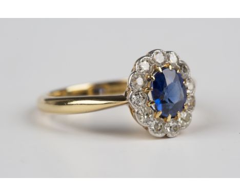 A gold, synthetic sapphire and diamond cluster ring, circa 1910, claw set with the cushion cut synthetic sapphire within a su