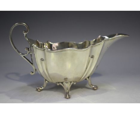 An Edwardian silver sauce boat of reeded and lobed form with scroll handle, on scroll legs, Sheffield 1904 by Goldsmiths &amp