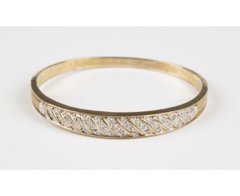 A 9ct gold and diamond oval hinged bangle, mounted with rows of circular cut diamonds in a slanting design, weight 15g, insid