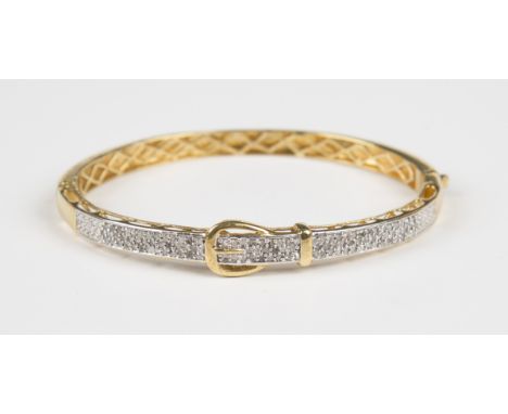 A silver gilt and diamond oval hinged bangle in a buckle and strap design, weight 14.8g, inside width 6.2cm.Buyer’s Premium 2