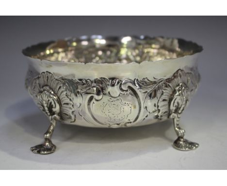A Victorian silver circular bowl, decorated in relief with flowers and scrolls, raised on stylized scallop shell shouldered s