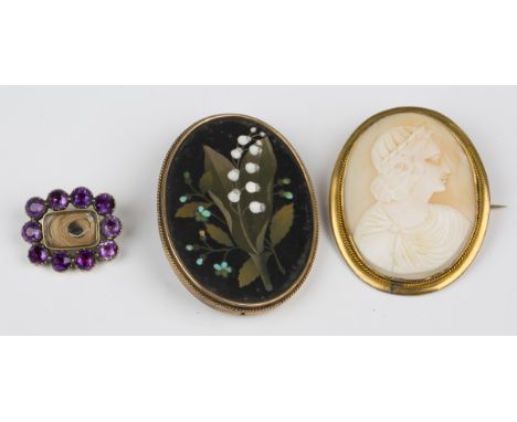 An early 19th century amethyst brooch of shaped rectangular form, glazed with a hair locket compartment within a surround of 