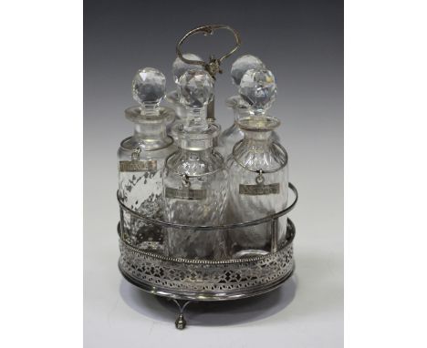 A George III silver cruet stand, the circular frame with pierced and engraved sides, fitted with five later glass bottles and