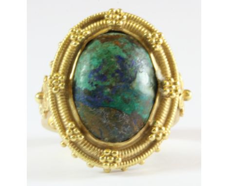 A high carat yellow gold (stamped 21k) filigree ring set with a cabochon cut stone, (R).