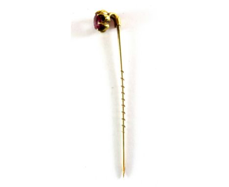 A yellow metal (tested minimum 9ct gold) stick pin set with an oval cut ruby in its original box, L. 6cm.