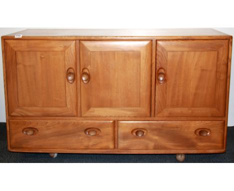 An Ercol cabinet (no label) with three cupboards and two drawers, W. 130cm, H. 77cm.