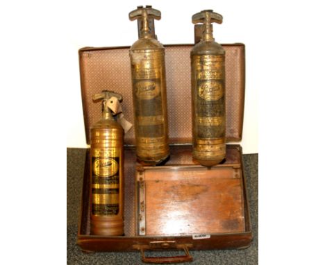 A vintage case containing three early fire extinguishers and an early desk trimmer.